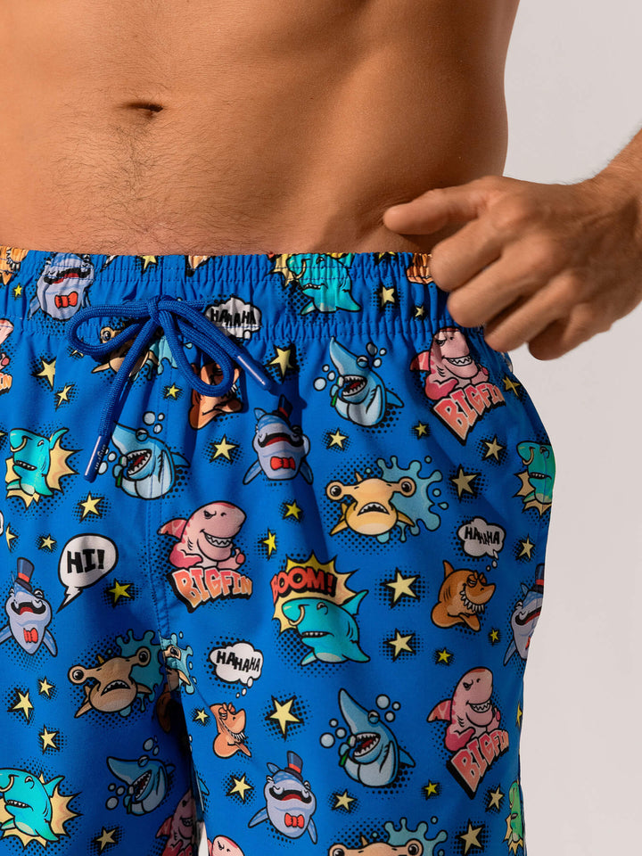 Blue swim shorts with cartoon shark design on a neutral background
