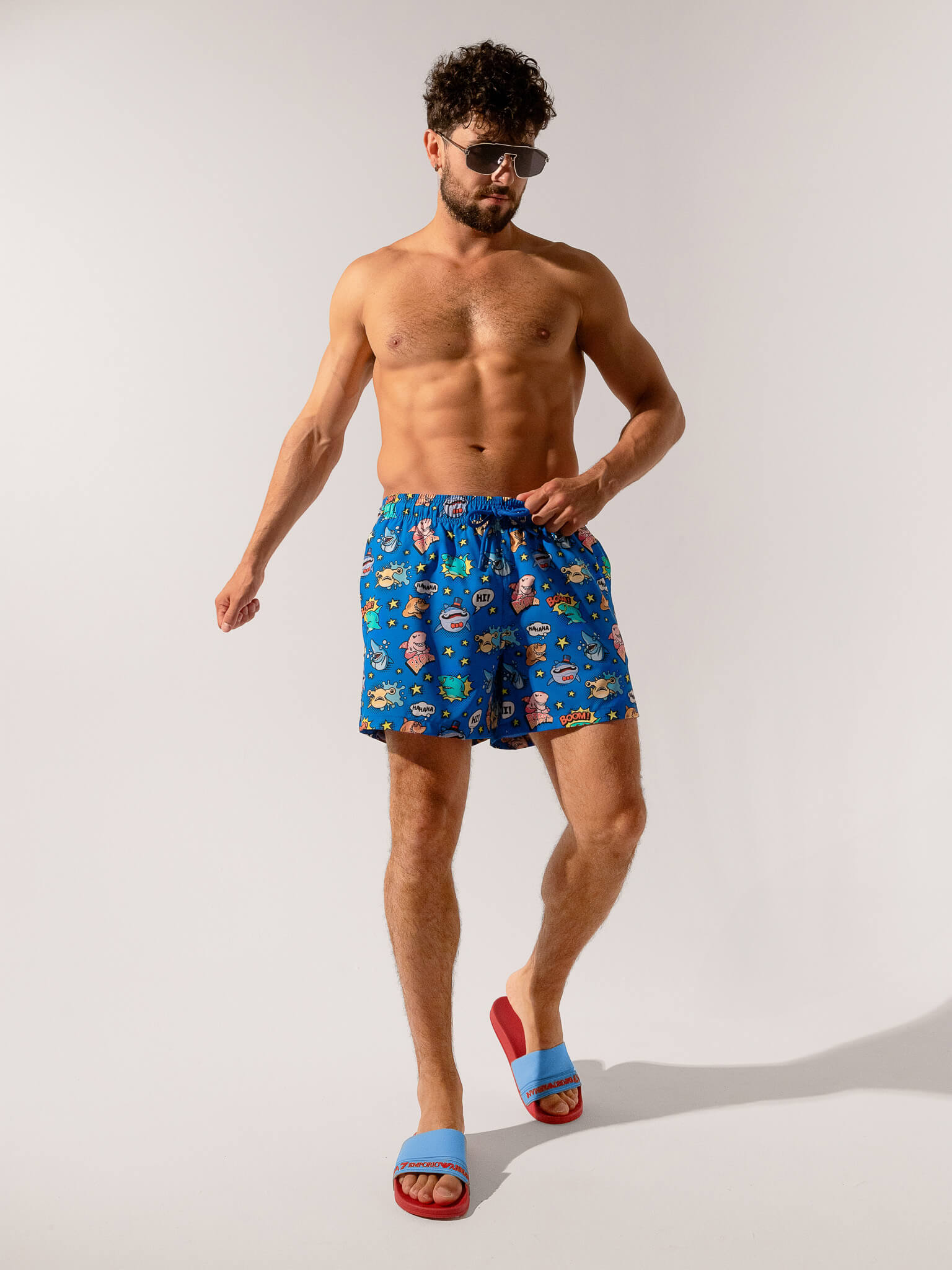 Man wearing blue swim shorts with a pattern on a white background