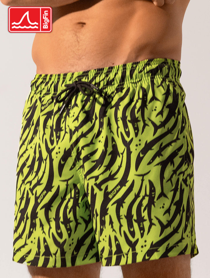 Green and black patterned swim shorts worn by a person on a white background, with BigFin logo.