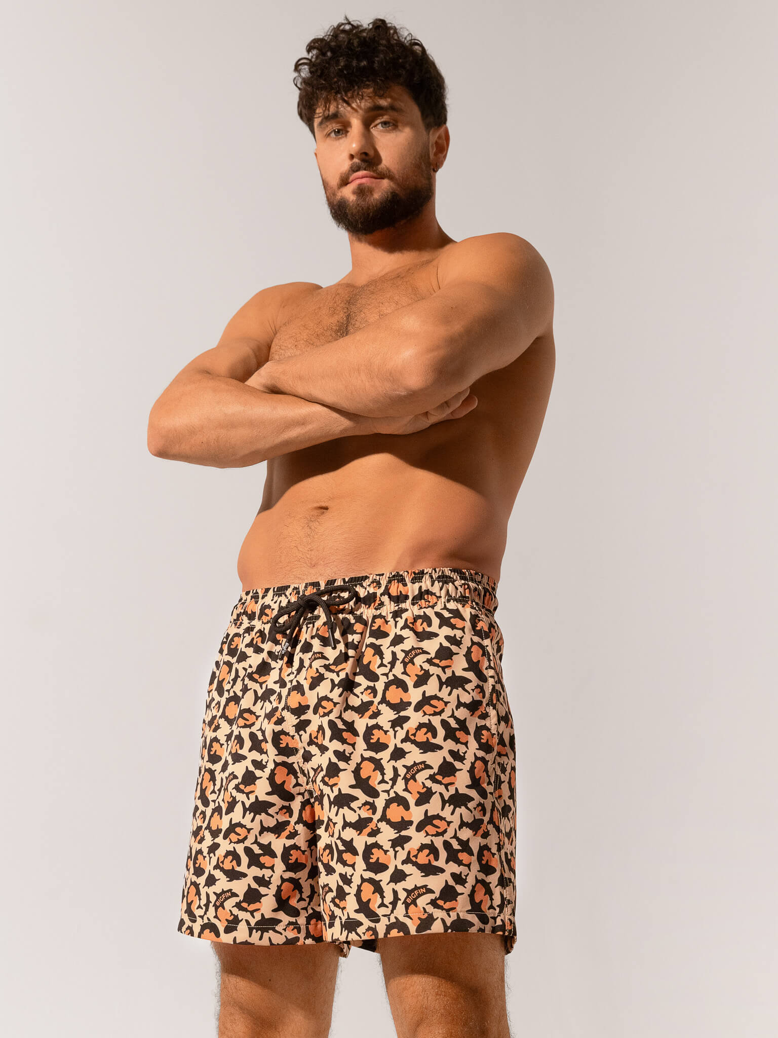 Man wearing leopard print swim shorts against a plain background