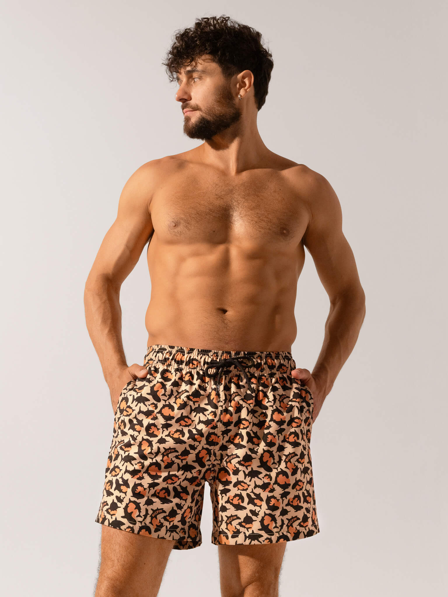 Man wearing leopard print swim shorts against a plain background