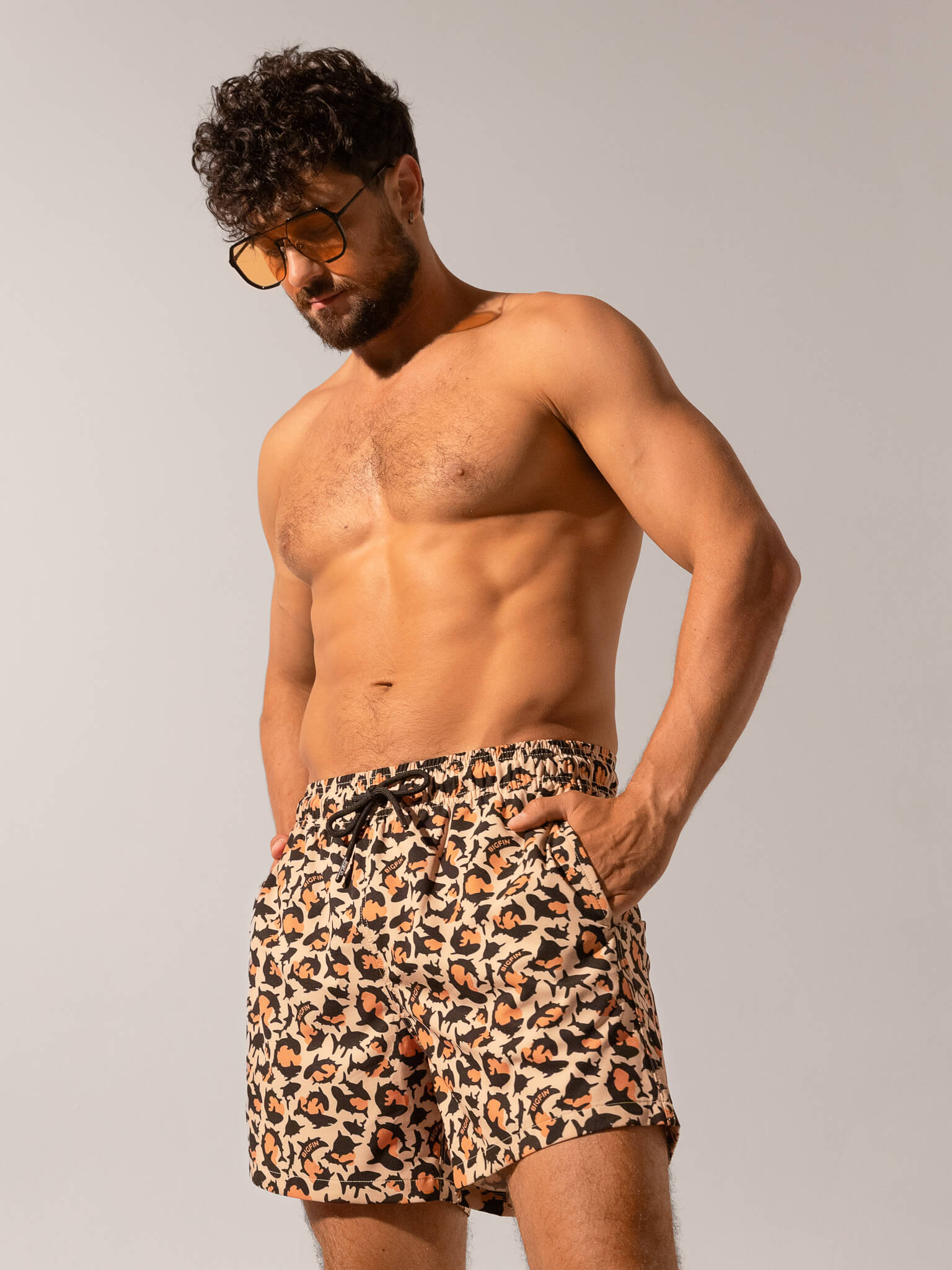 Man wearing leopard print swim shorts against a plain background
