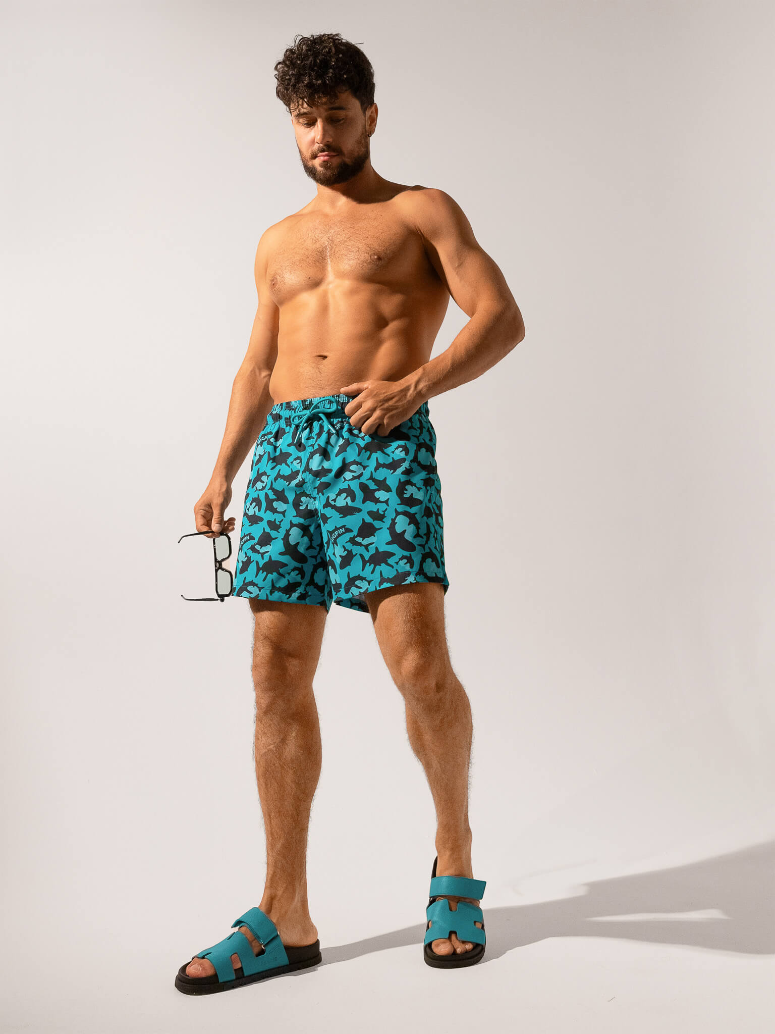 Man wearing blue swim shorts with a pattern on a white background