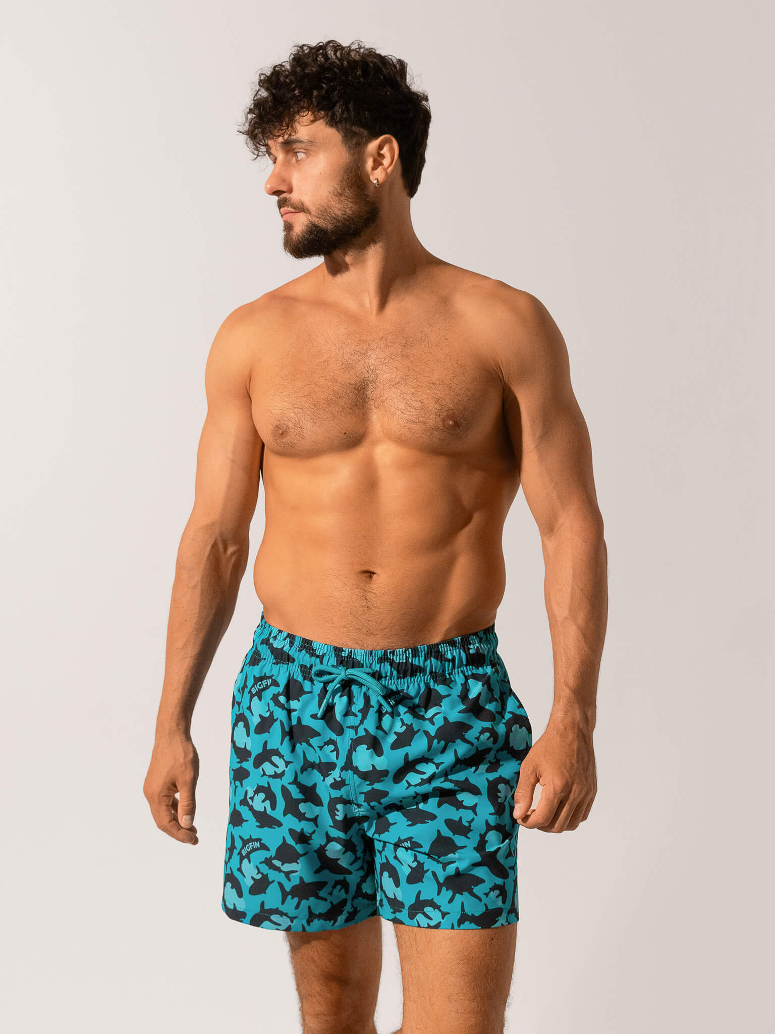 Man wearing blue camouflage swim shorts on a white background