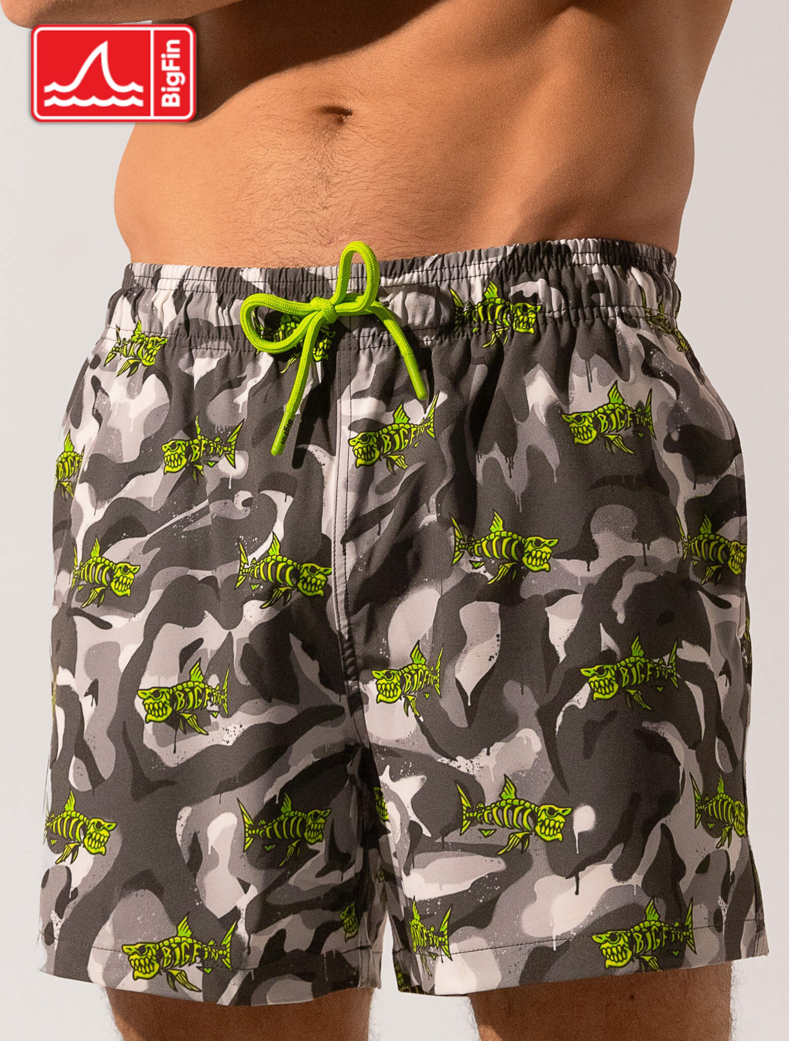 Gray camouflage swim shorts with green accents on a white background, featuring the Bigfin brand logo.