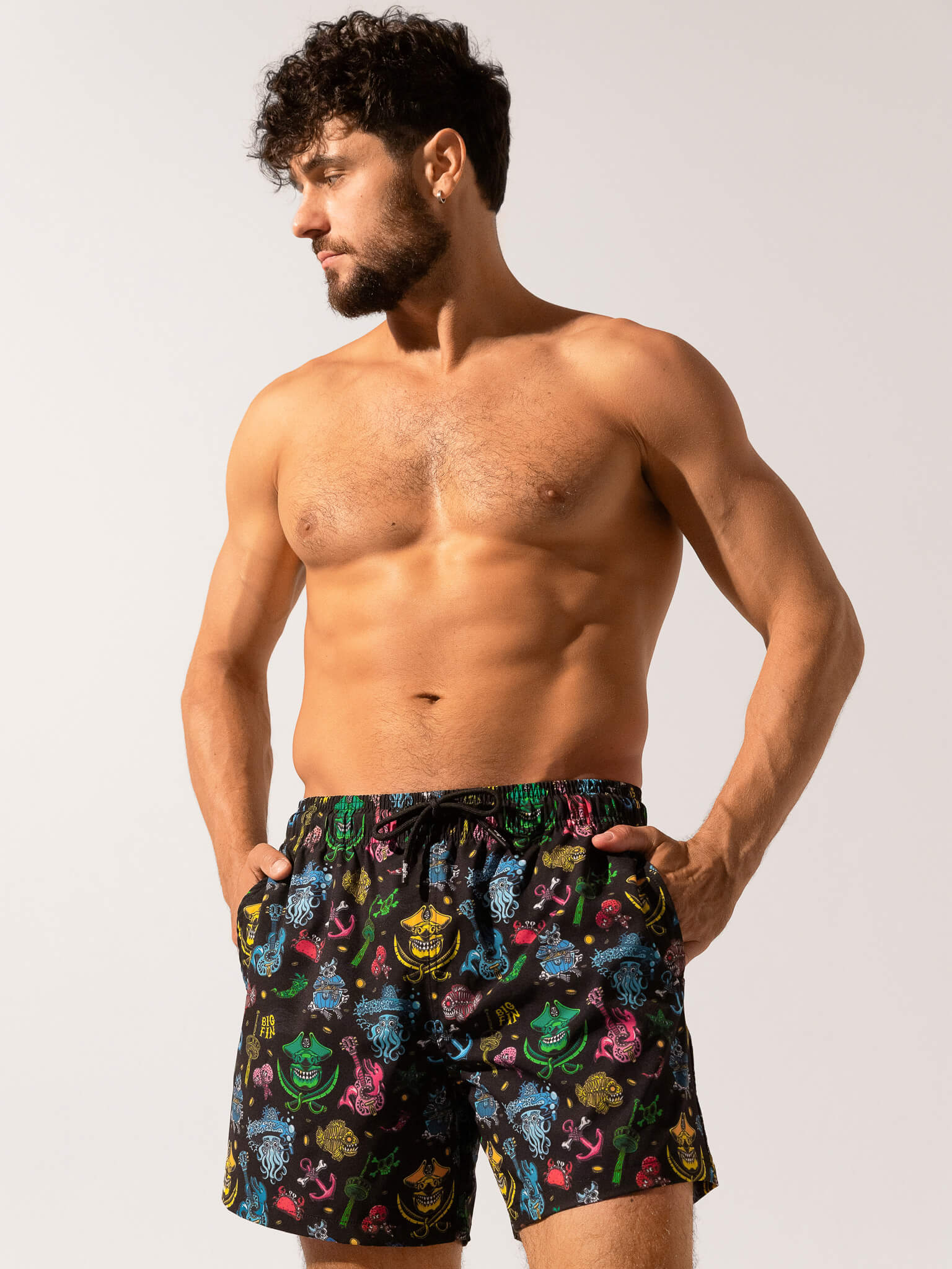 Man wearing colorful patterned swim shorts on a plain background