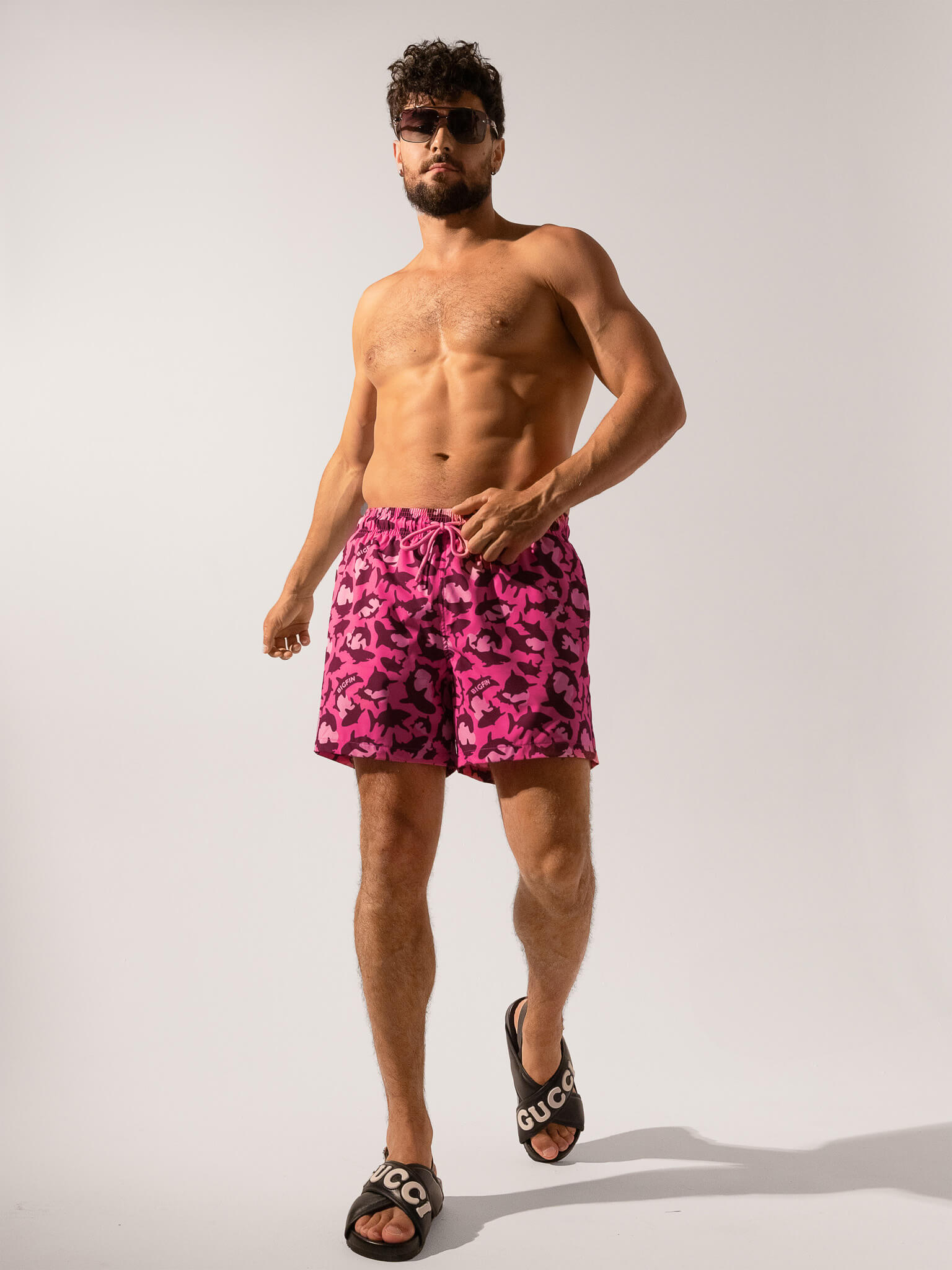 Man wearing pink camouflage swim shorts on a white background